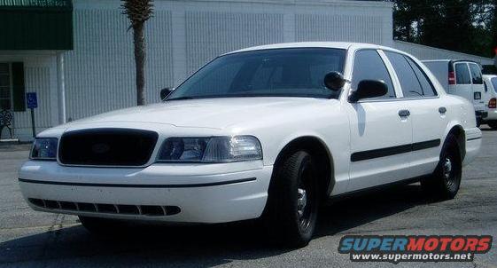 White sedan parked outside a building, with a palm tree and a white van in the background