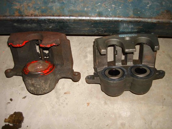 Two brake calipers, one rusty with red paint, one clean