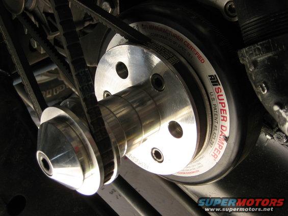 Close-up of a polished metal ATI Super Damper pulley with multiple V-belts
