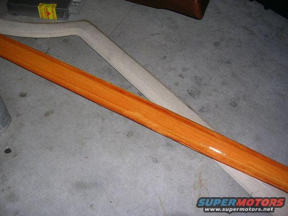 Orange-stained wood trim piece and a lighter wood piece on a concrete floor