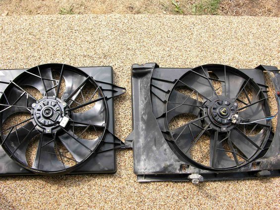 Two black radiator fans side-by-side on gravel