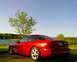 1993 Ford Probe - A red 1993 Ford Probe GT is parked near a body of water under a clear blue sky.