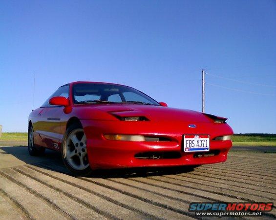Red 1993 Ford Probe GT parked on a concrete surface under a clear blue sky
