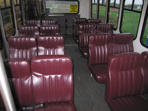 Interior of bus with maroon vinyl seats and windows showing a grassy field
