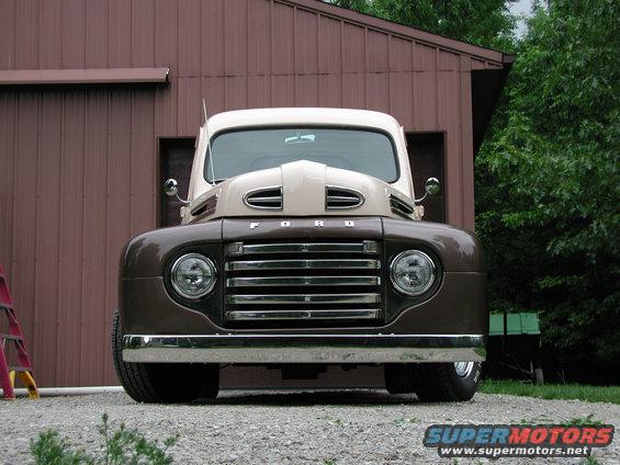 Brown and tan Ford truck front view, grille with horizontal bars, round headlights, "FORD" lettering on hood