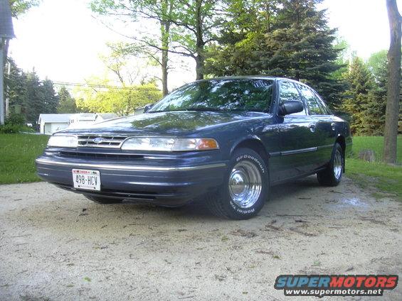 Dark blue Ford Crown Victoria parked on a dirt road. It has a Wisconsin license plate