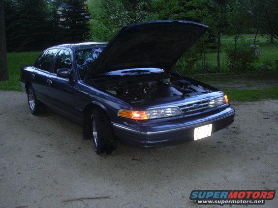 Dark blue sedan, hood open showing engine. Looks like a Ford Crown Victoria, but maybe an earlier model than 1996