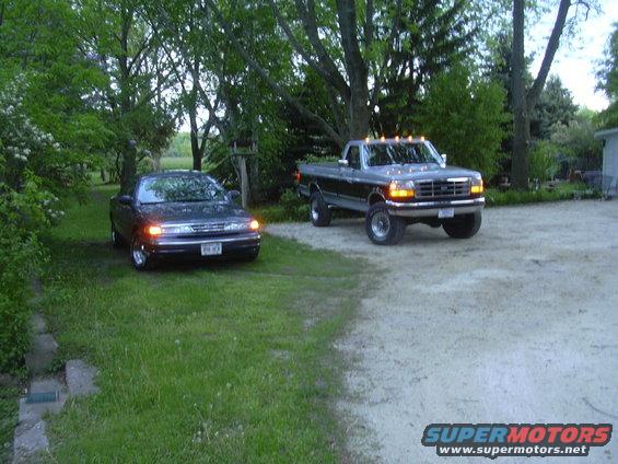 Ford F-250 pickup truck parked next to a Ford Crown Victoria on a gravel driveway