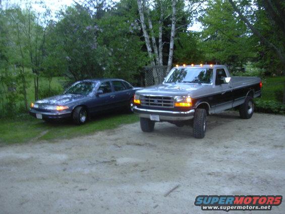 Dark blue sedan parked next to a lifted pickup truck