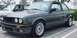 1989 BMW 3 Series - A 1989 BMW 3 Series coupe is parked in a lot, with another vehicle partially visible behind it.
