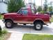 1994 Ford Bronco - Side profile of a red 1994 Ford Bronco with tan trim, showing its removable top configuration.