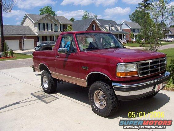Red Ford Bronco with tan trim, lifted, on a driveway