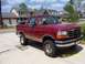 1994 Ford Bronco - This red Ford Bronco with tan trim is parked in a suburban driveway.