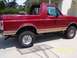 1994 Ford Bronco - Side view of a red 1994 Ford Bronco with its top removed, parked outdoors.