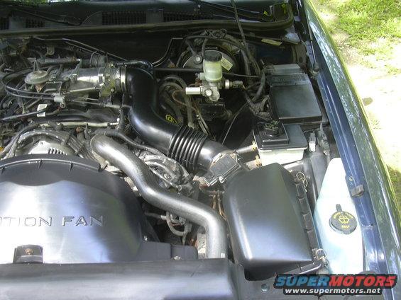 Engine bay with air intake, fan shroud, and brake fluid reservoir visible