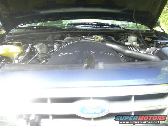 Engine bay with Ford logo on grille. Caution fan cover visible