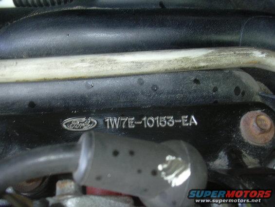 Ford logo and part number 1W7E-10153-EA stamped on black engine component