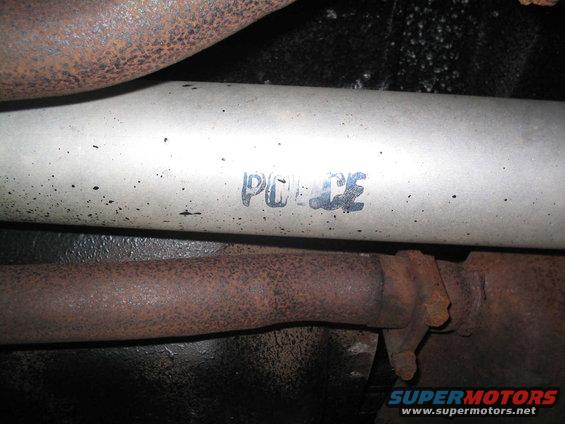 Exhaust pipe with "POLICE" stencil, showing rust and black speckles
