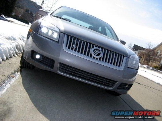 Gray sedan front grille with Mercury logo, daytime, snow on the side