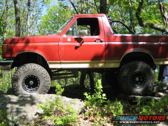 red Ford Bronco on rocks, lifted suspension, off-road tires