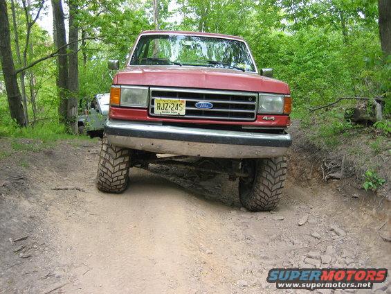 Red 1990 Ford Bronco front view on dirt trail with 4x4 badge