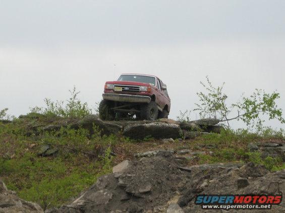 Red 1990 Ford Bronco climbing rocky terrain
