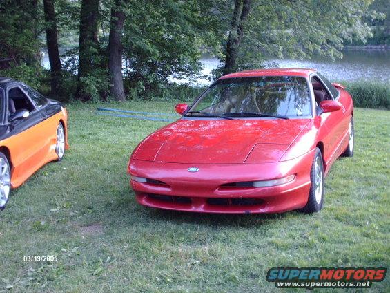 Red 1995 Ford Probe parked on grass next to another car