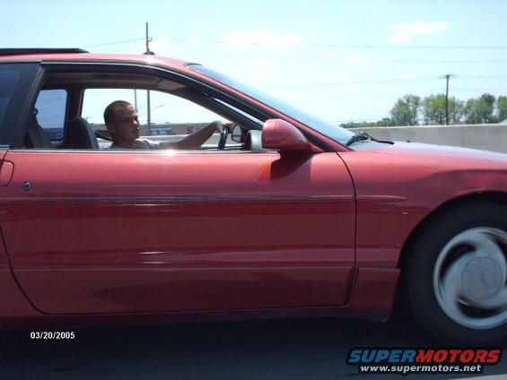 Red 1995 Ford Probe coupe driving on a highway, side view, driver visible