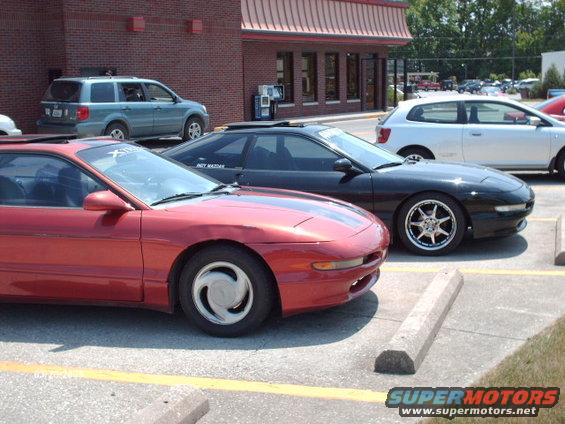 Red 1995 Ford Probe in foreground, black 1995 Ford Probe behind it, parked in lot