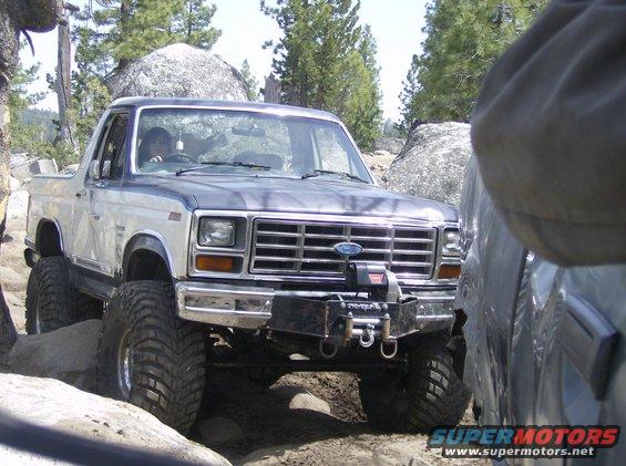 Two-tone 1986 Ford Bronco with winch on rocky terrain