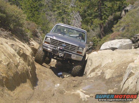 Ford Bronco navigating a rocky, off-road trail. Winch mounted on front bumper