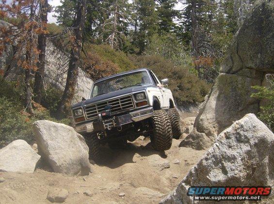 Modified Ford Bronco with large tires navigating a rocky trail