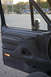 1995 Ford Bronco - Interior view of a 1995 Ford Bronco, showing the driver's side door panel and the exterior scene through the open door.