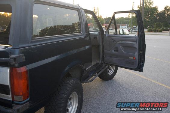 Dark blue Ford Bronco with doors open, parked in a lot