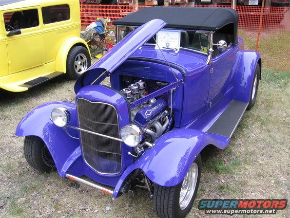 Purple convertible hot rod with open hood and Chevrolet engine. Yellow car in background