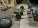 1962 Ford Thunderbird - The rear axle assembly of a car is shown on the floor, with a jack and creeper nearby.