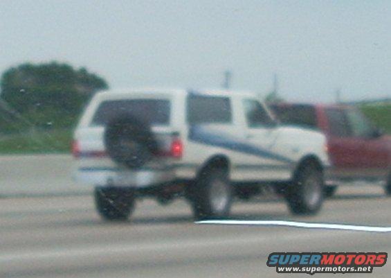 White 1992 Ford Bronco with blue stripe and rear spare tire