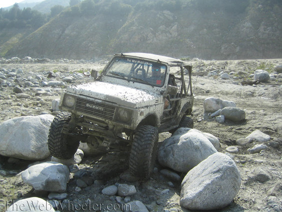 1987 Suzuki Samurai navigating large rocks in a dry riverbed