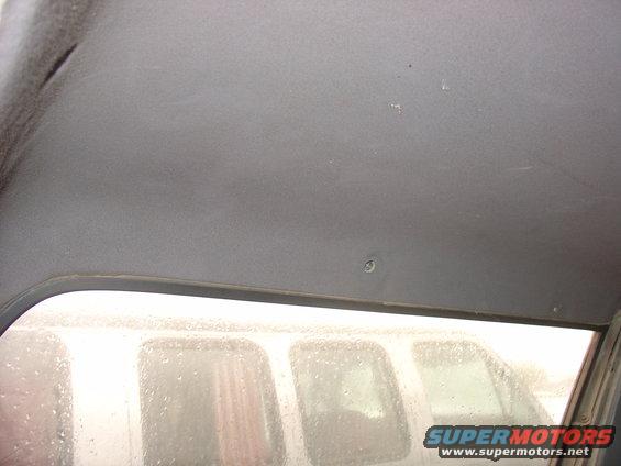 View of a gray headliner inside a vehicle, looking out a window at other vehicles