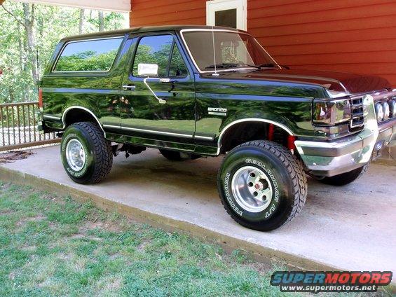 Black lifted Ford Bronco parked on a concrete pad, side view