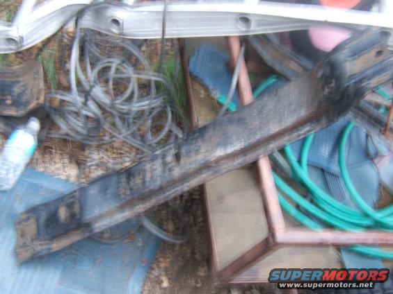 Close-up of a dirty metal automotive part, possibly a frame rail