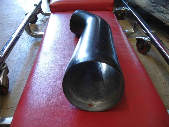 Black curved air intake tube resting on a red padded surface with chrome legs
