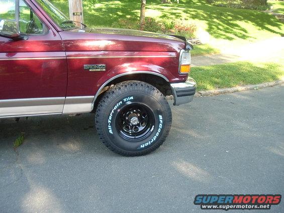 Maroon 1996 Ford Bronco front fender and tire, with chrome bumper and trim