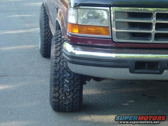 Front corner of a dark red Ford F-Series truck with aftermarket tires
