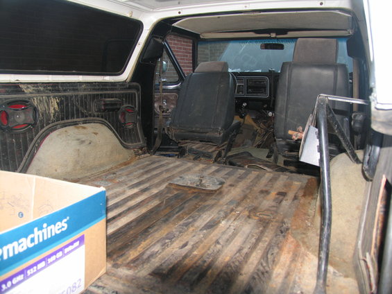 Interior of a 1978 Ford Bronco with worn seats and a ribbed metal floor