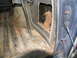 1978 Ford Bronco - The interior of a vehicle shows significant damage to the door panel and rust on the floor.