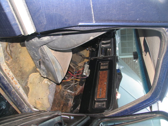 Interior view of a blue vehicle showing exposed wiring and a wood-grain trim panel