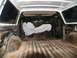 1978 Ford Bronco - The cargo area of a white SUV is shown, with a tarp-covered object obscuring the view of the rear seats.