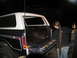 1978 Ford Bronco - A person pressure washes the bed of a 1978 Ford Bronco, which is dark blue with a white camper shell.