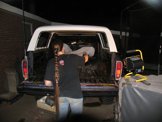 1978 Ford Bronco with white camper shell, person cleaning out the bed